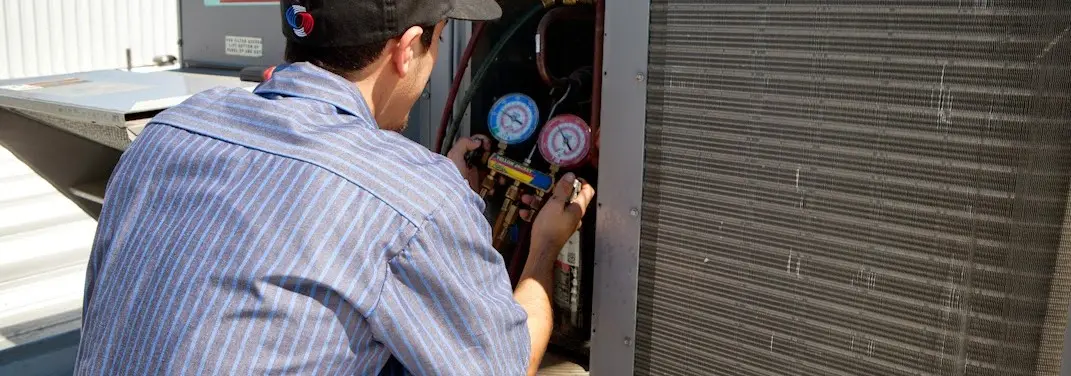 HVAC technician servicing a condenser unit in Honey Brook